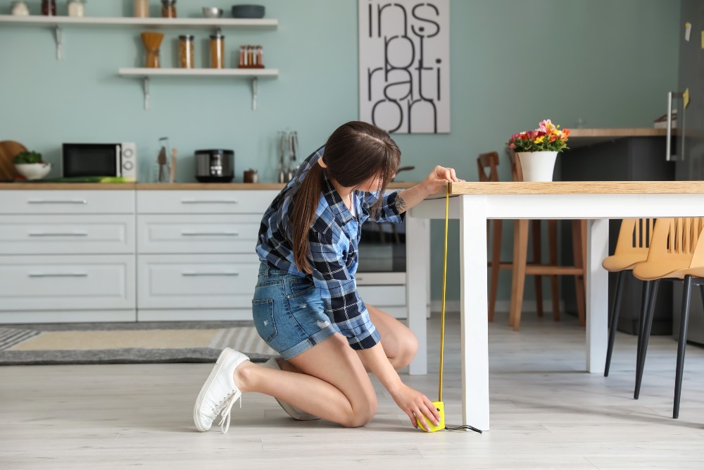Woman measuring table to make sure she has room for it while downsizing her house