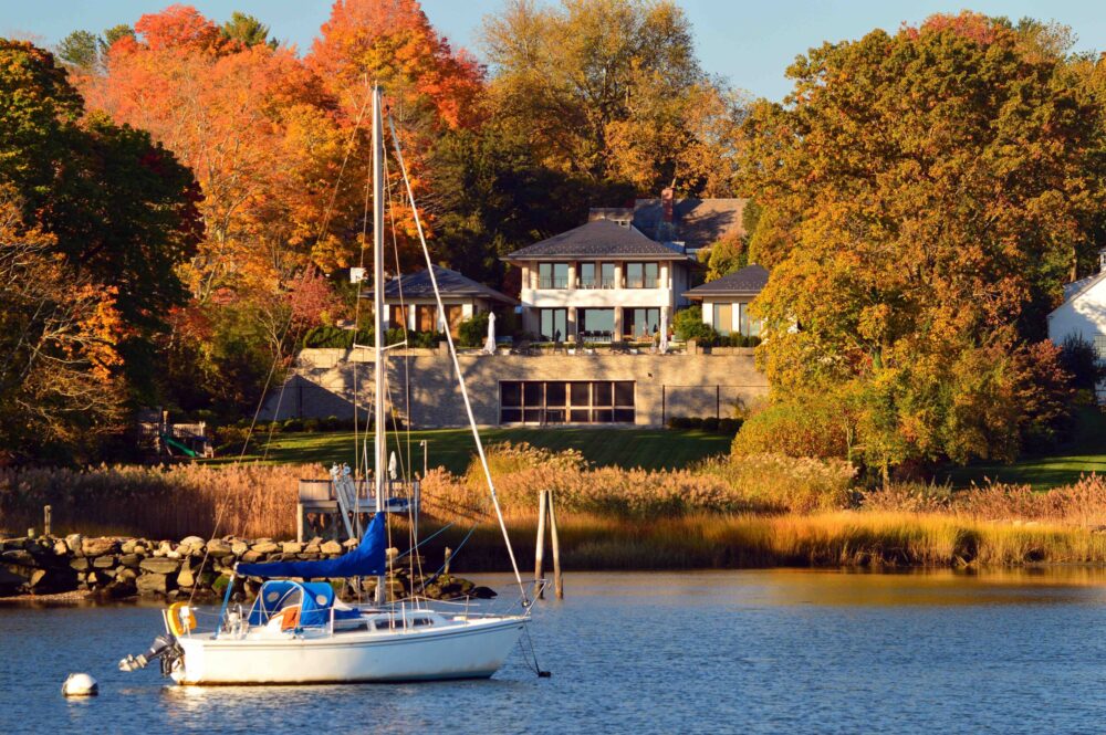 Sail boat in front of a beautiful waterfront property